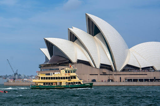 A green and yellow Sydney ferry on Sydney Harbour with the Opera House backdrop symbolising Australian coastal cruising.