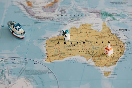 Miniature boat and lighthouse figurines on a nautical map of Australia showing charts available at Boat Books Australia.